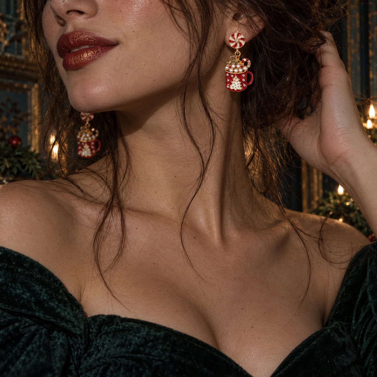 A close-up lifestyle shot of a woman wearing festive red and gold holiday earrings with a candy cane and snowman mug design, paired with a dark green velvet off-the-shoulder top.