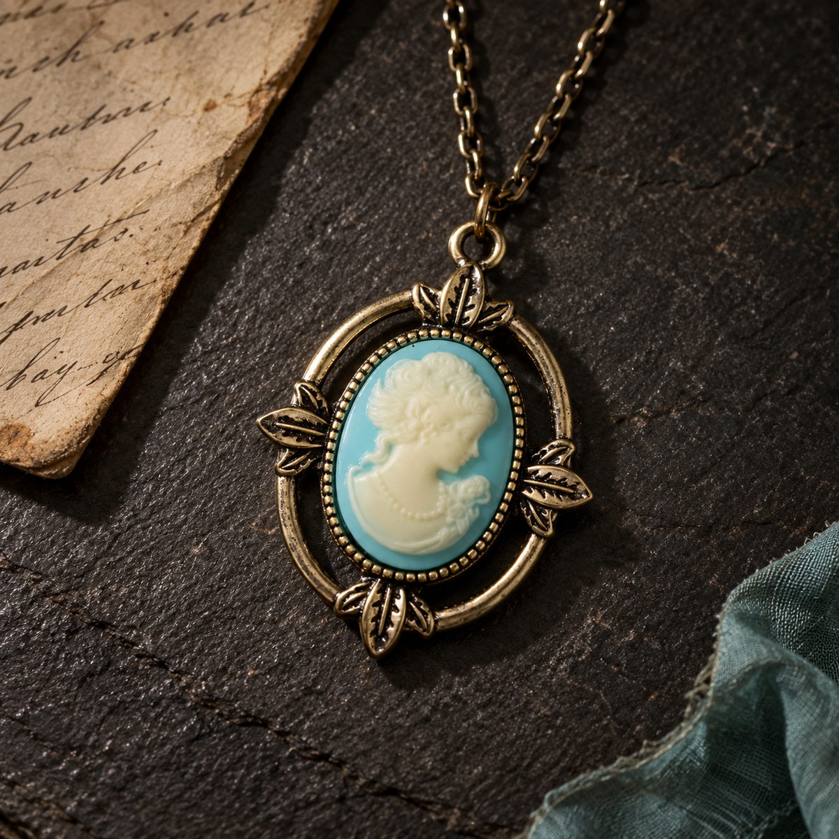 An antique-style oval pendant necklace with a light blue and cream cameo profile in the center, set in an aged bronze-toned metal frame and hanging from a matching chain on a dark textured surface.