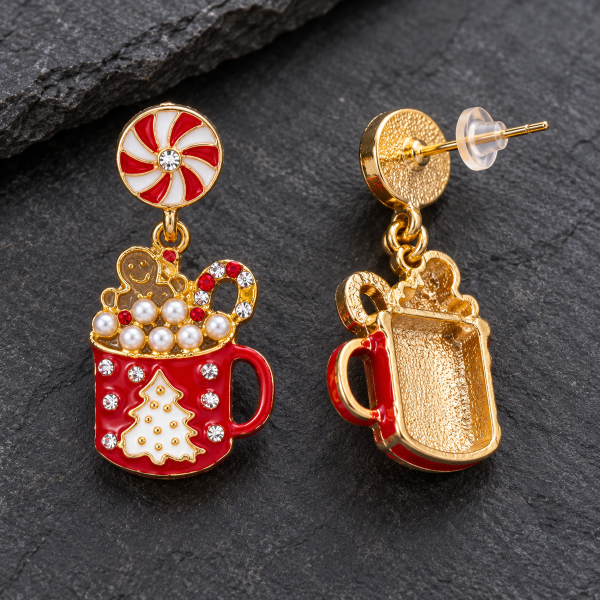A pair of gold-tone and red enamel Christmas mug earrings with white and red candy cane details, displayed on a dark slate background.